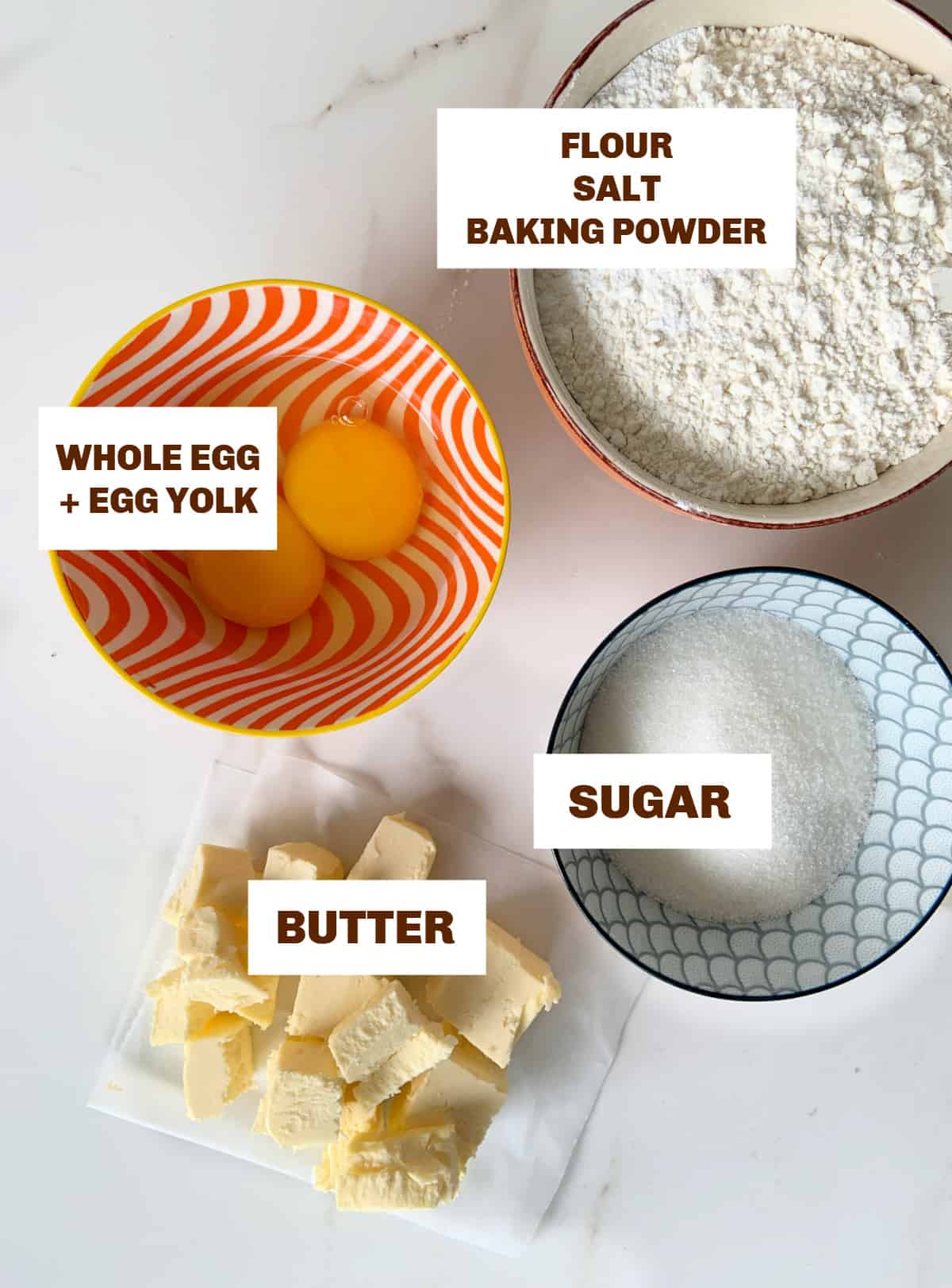 White surface with colored bowls of ingredients for making sweet pie dough