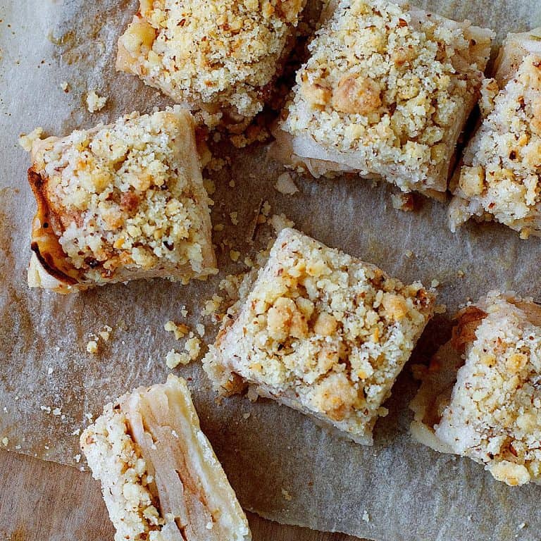 Apple crumb squares seen from the top on a thin parchment paper on a wooden board