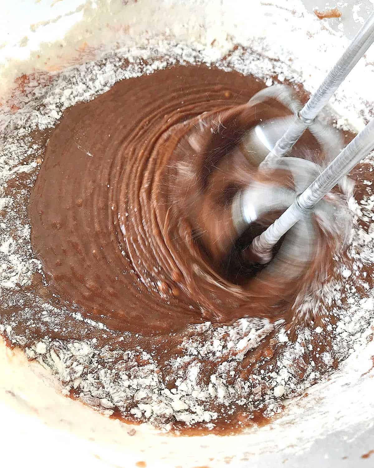 Mixing chocolate cake batter with an electric mixer.