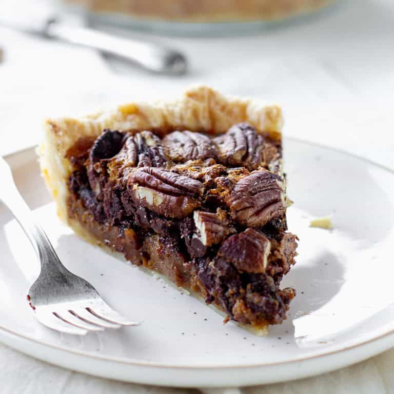 White background and plate with slice of pecan pie, a silver fork