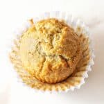 A single golden muffin on a white surface, open paper liner