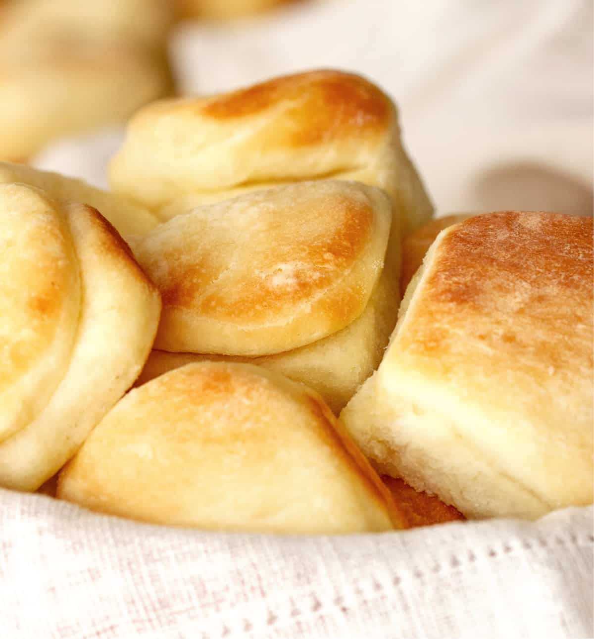 Small dinner rolls stacked on a white cloth.