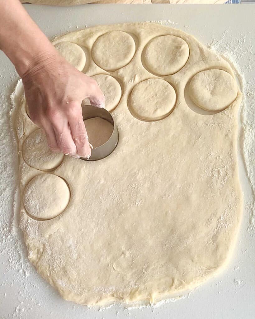 Rolled bread dough and hand cutting rounds with a cookie cutter.