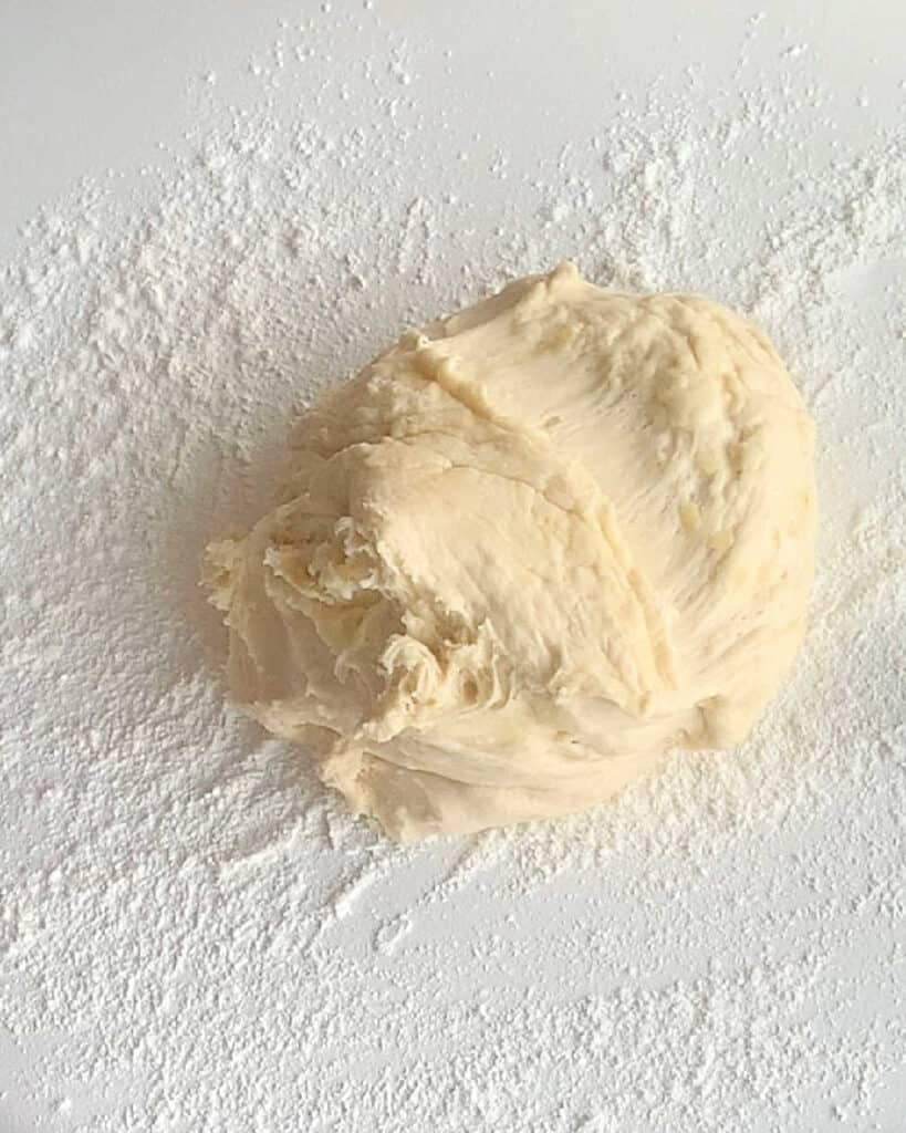 Parker house rolls dough on a floured white surface.