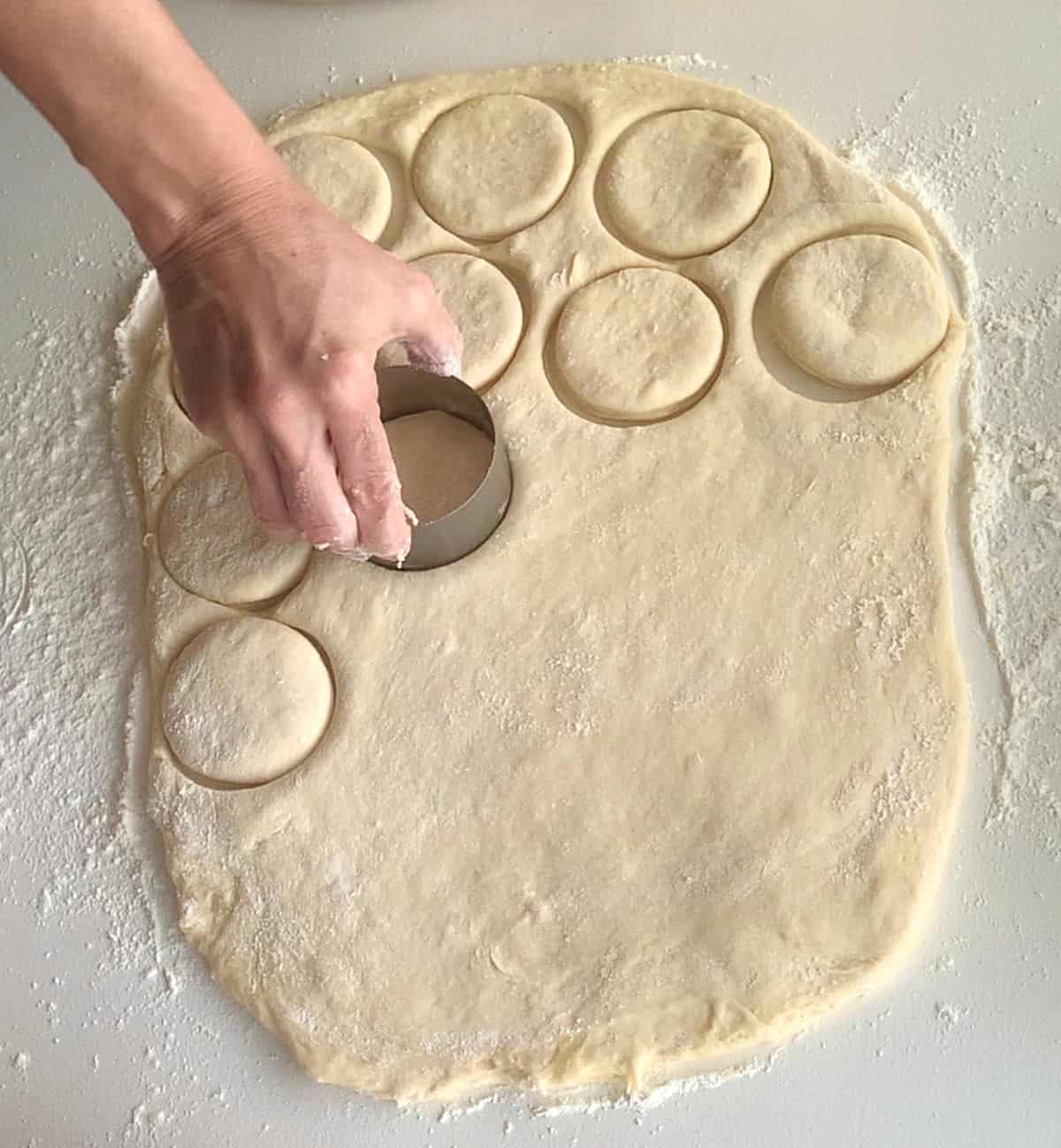 Cutting rounds from rolled dough on a white floured surface