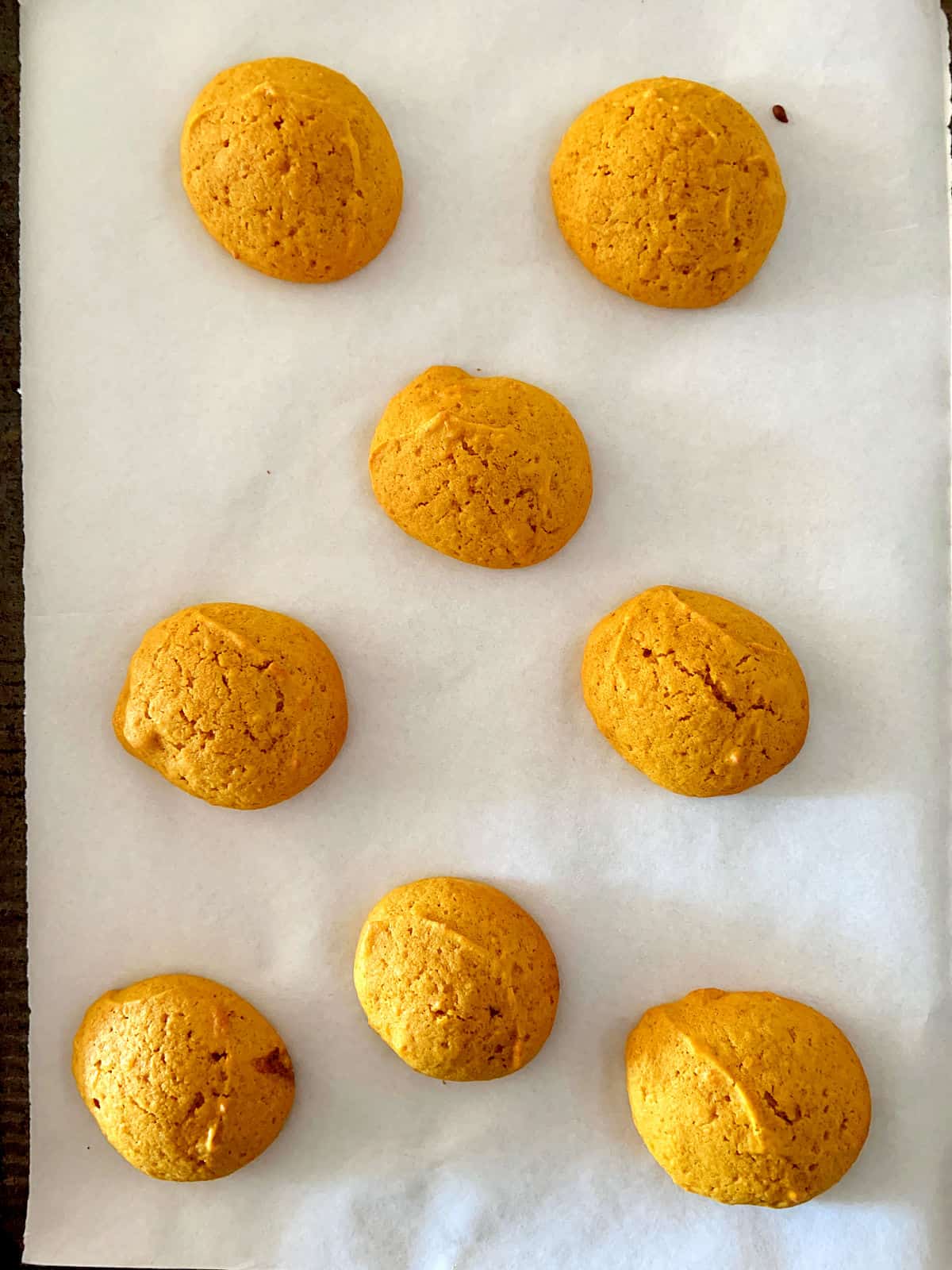 Baked pumpkin soft cookies on white parchment paper