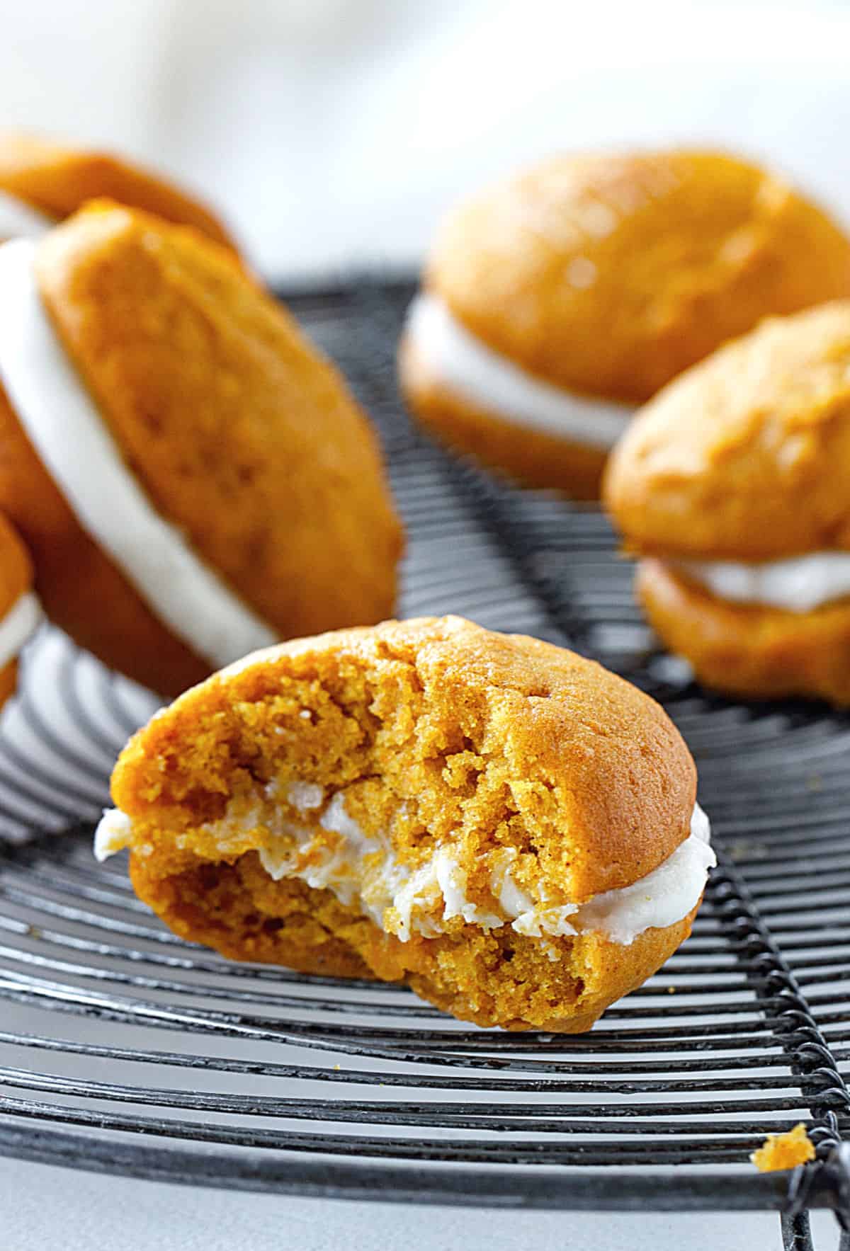 On a wire rack half a pumpkin whoopie pie, filling showing