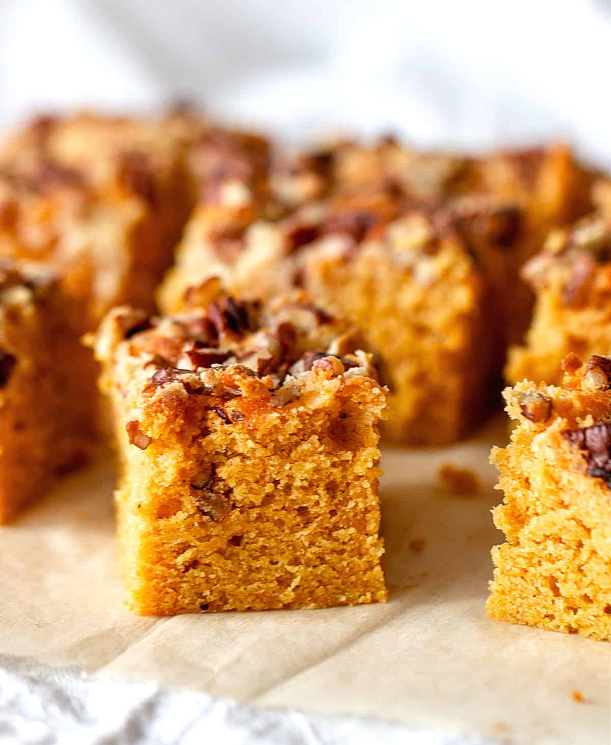 On brownish parchment paper, squares of pecan topped pumpkin sheet cake