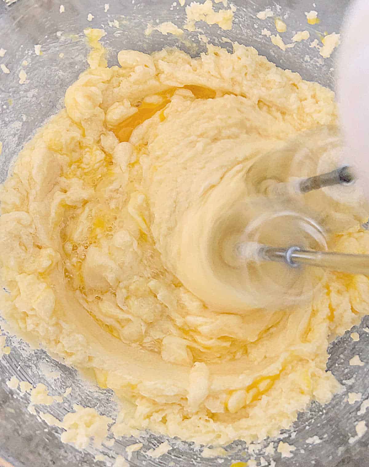 Beating vanilla cake batter in a glass bowl, grey surface