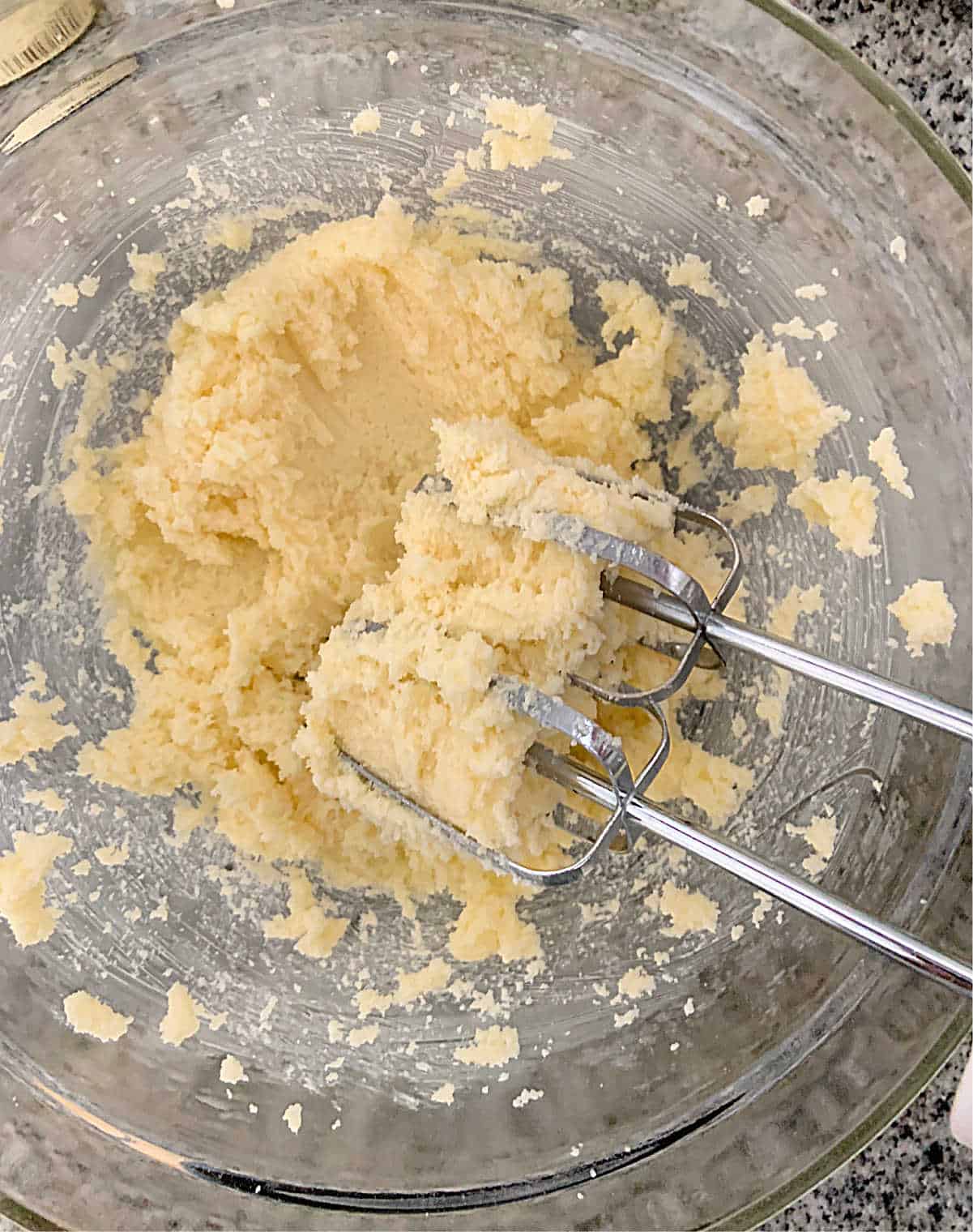 Cake batter in glass bowl with metal beaters inside
