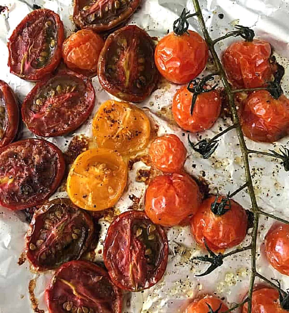 Baked tomatoes, halved and whole, on piece of aluminum paper