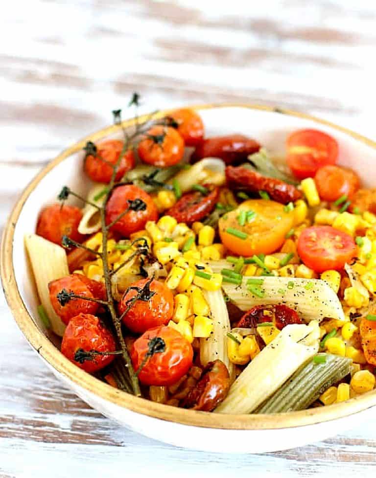 Close up of pasta cream and gold bowl with corn and tomatoes