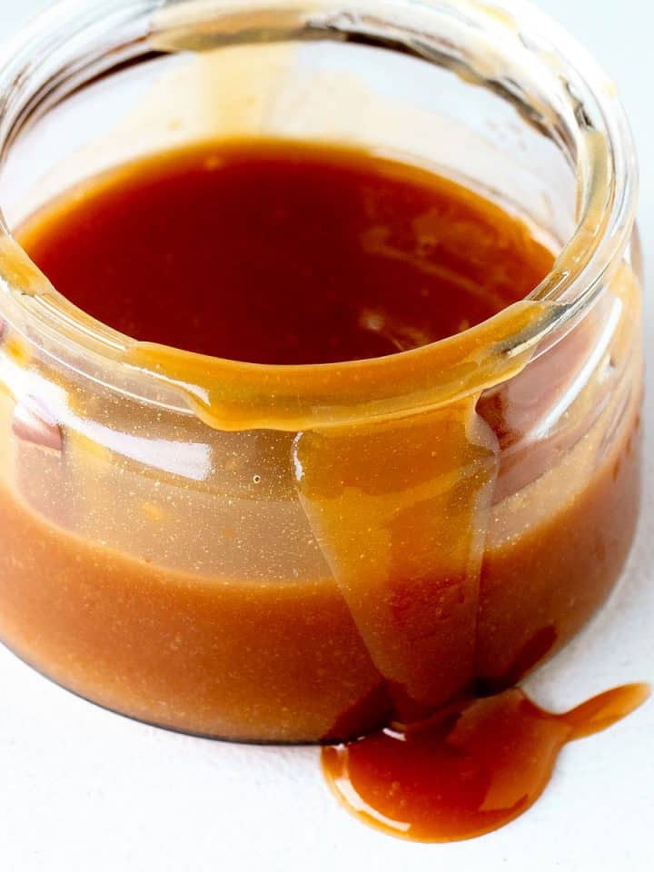 Close up of jar with dulce de leche on a white surface