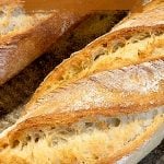 Golden loaf of bread on metal pan, brown overlay and white text