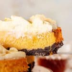 Gray background with a slice of pumpkin cheesecake topped with cream.