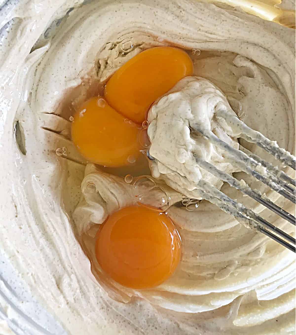 Mixing eggs with cream cheese, hand beater