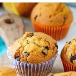 Wooden board with several pumpkin muffins in colorful paper liners, brown text