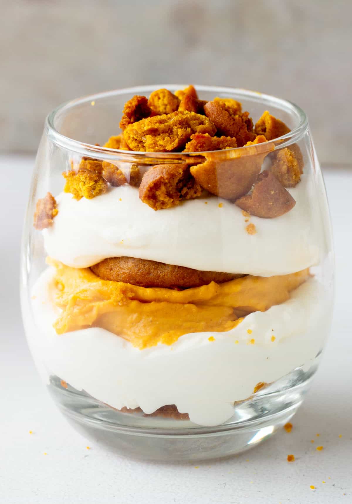 Single glass with pumpkin cream trifle on a white surface with grey background. 