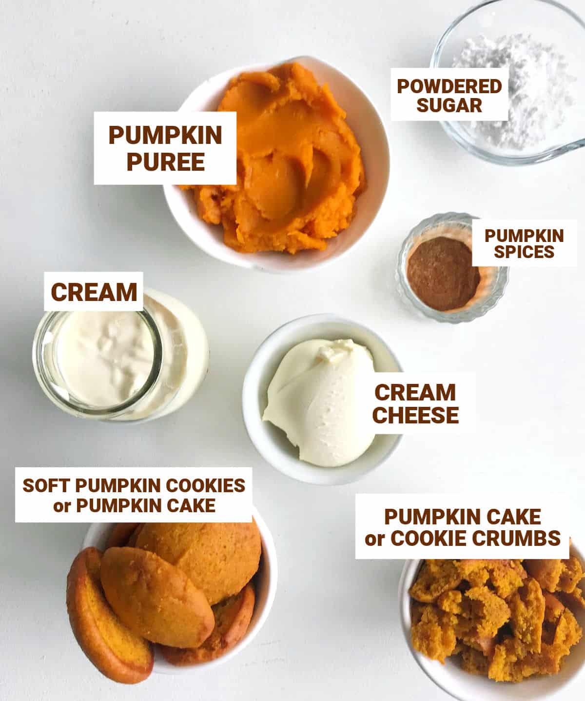 Bowls with ingredients for pumpkin trifle on a white surface including pumpkin cookies, cream, cream cheese, sugar, spices.