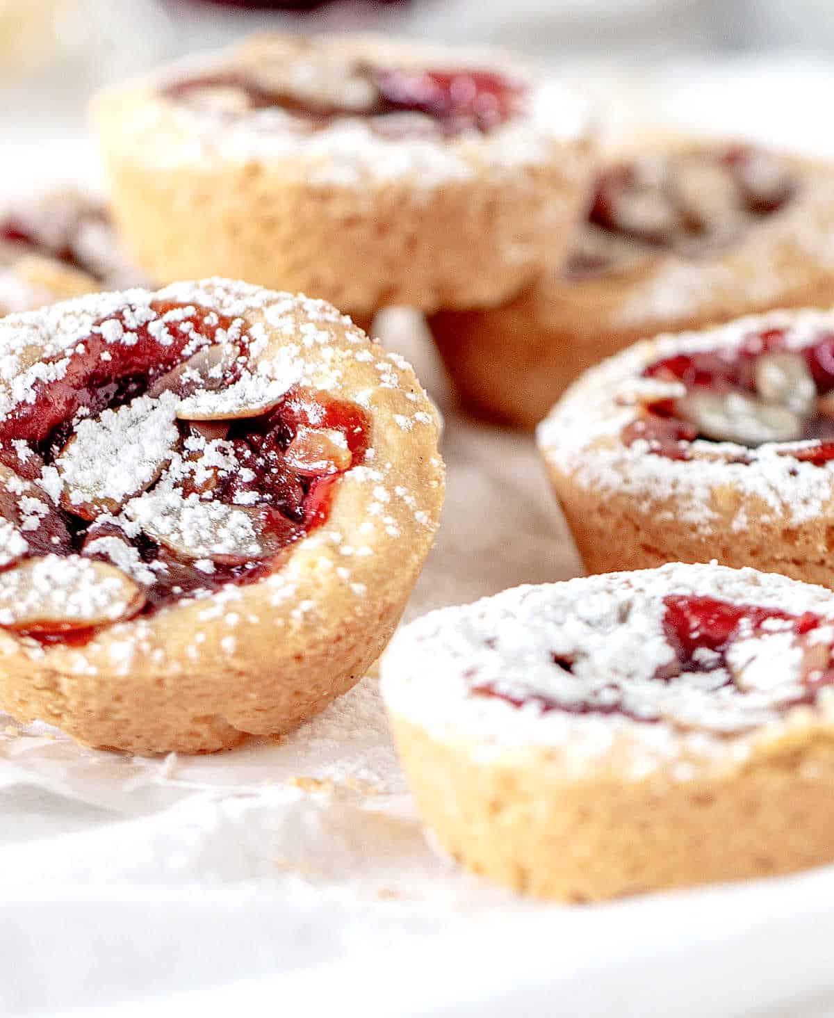 Close up of several almond jam mini tarts on a white kitchen towel.