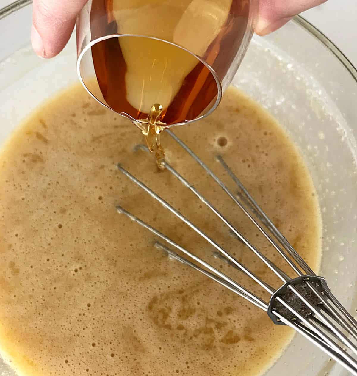 Adding small glass of bourbon to bowl with butter and eggs mixture.