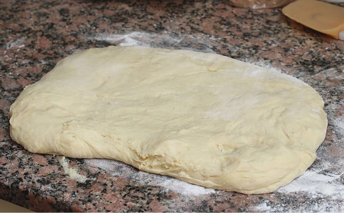 Rectangle of dough on brownish marble countertop