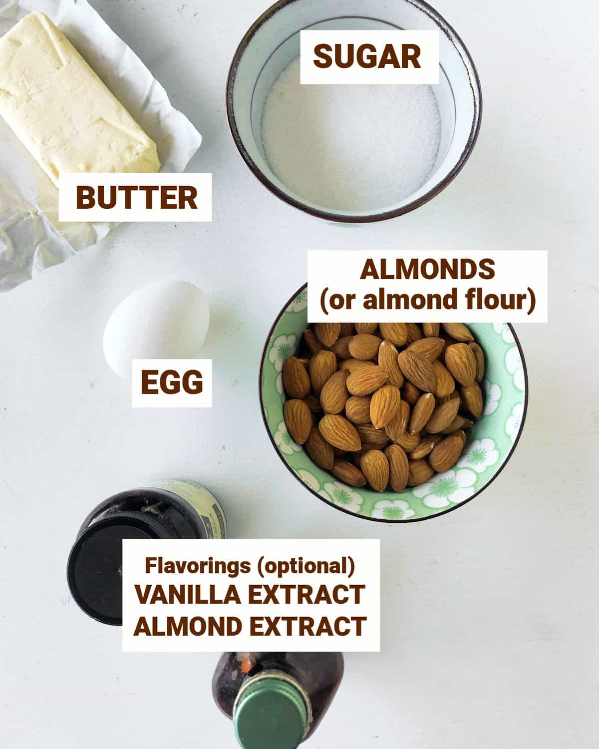 Ingredients for almond cream in bowls on a white surface including butter, sugar, egg, flavorings.