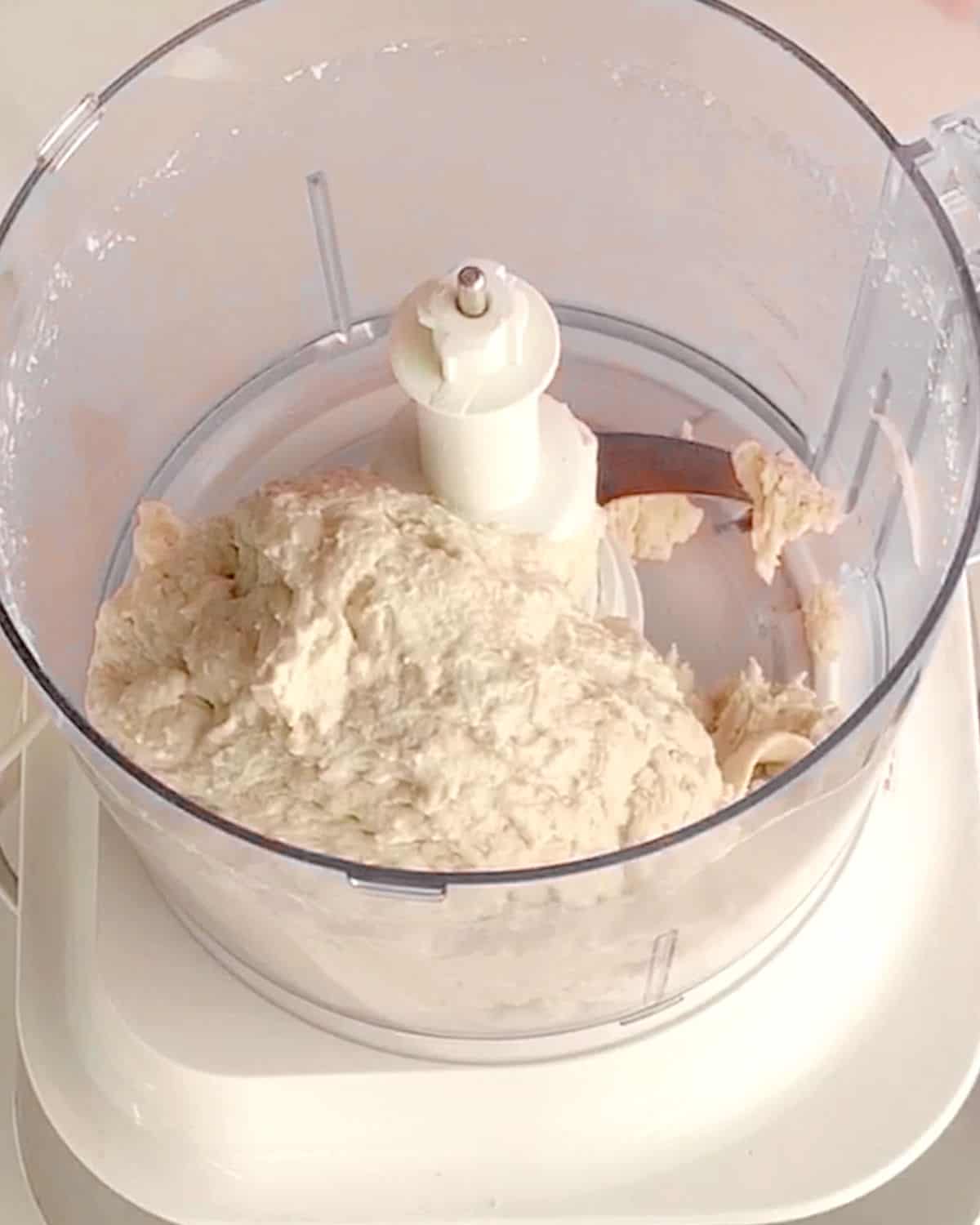Bread dough in the bowl of a food processor. View from above.