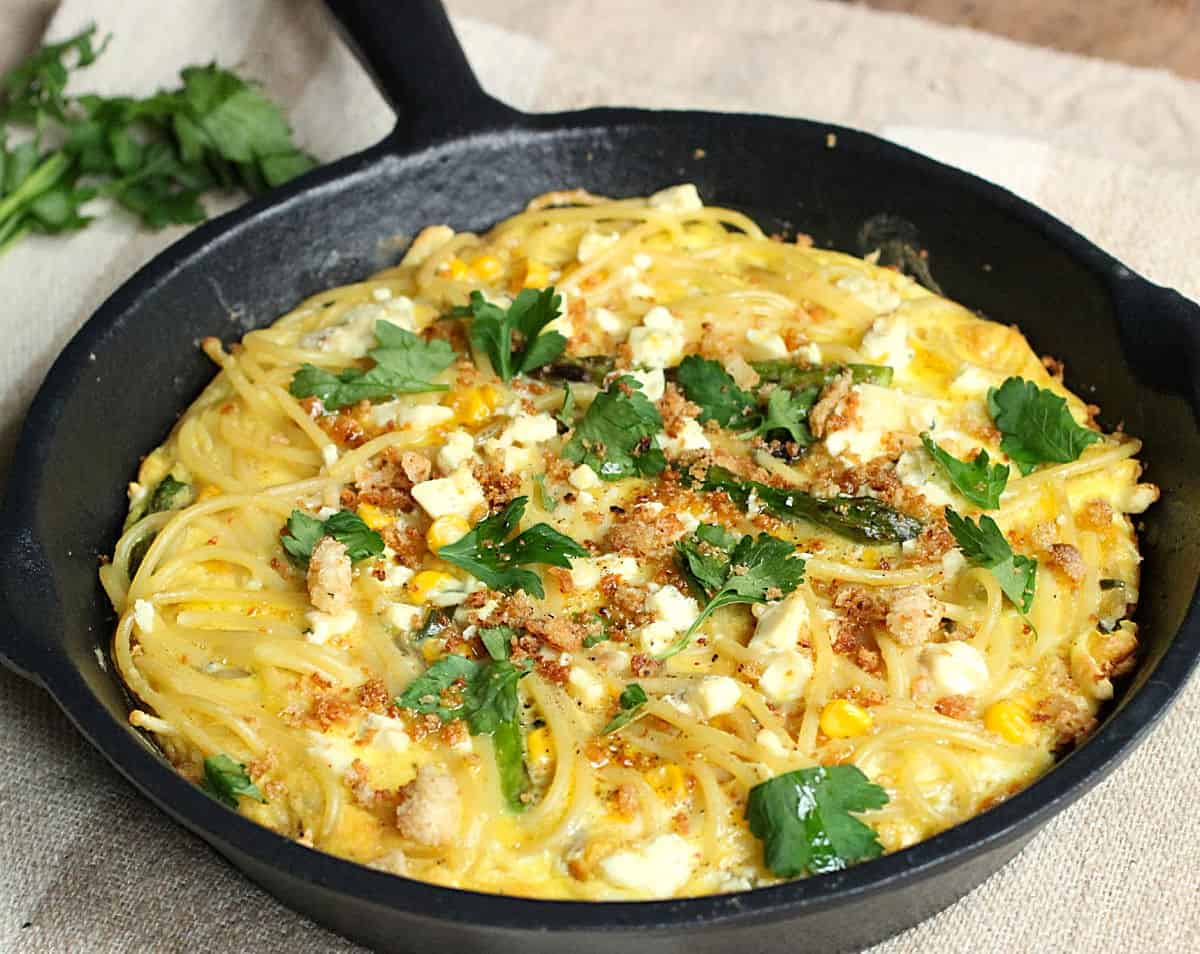 Frittata of pasta in cast iron skillet on beige cloth