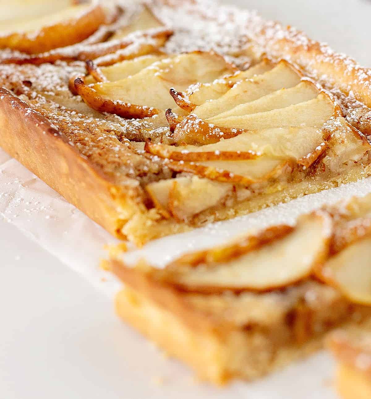 Partial view of pear frangipane tart on white surface