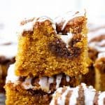 Several stacked squares of pumpkin cake with glaze, brown text