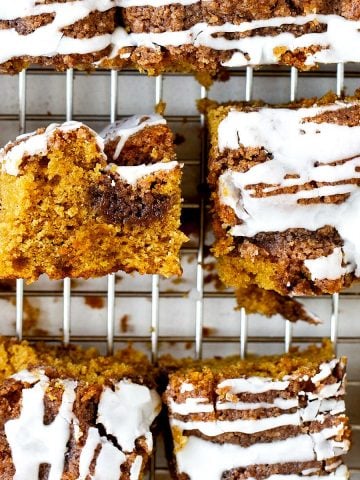 Squares of iced pumpkin coffee cake on a wire rack.