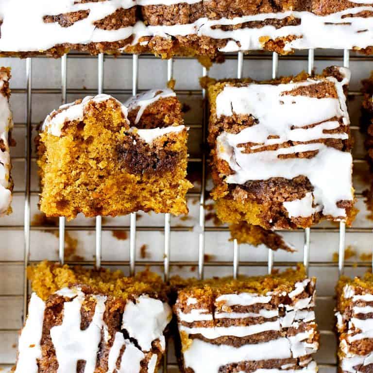 Squares of iced pumpkin coffee cake on a wire rack.