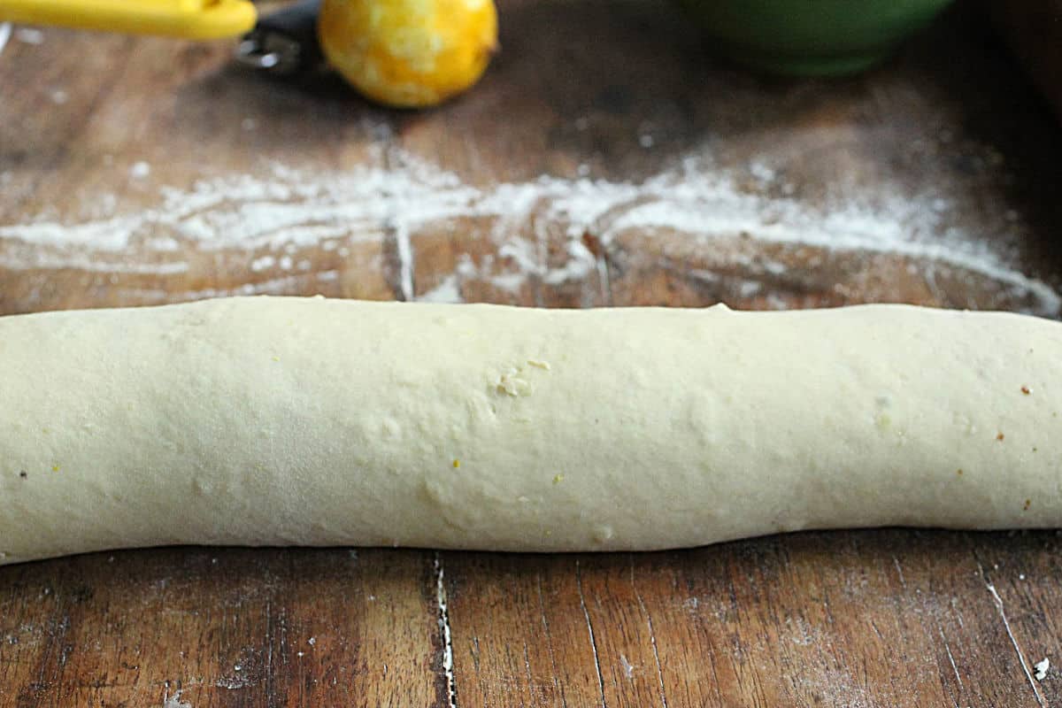 Rolled bread dough on a wooden table, whole lemon in background