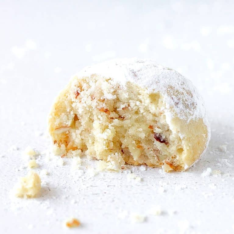 Crumbly round butter cookie, bitten, white surface with crumbs and powdered sugar.