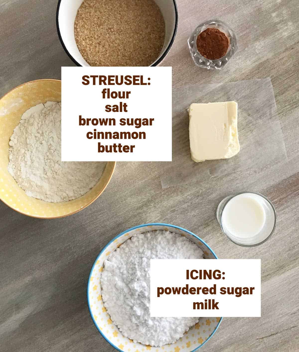 Colored bowls with ingredients for brown sugar cinnamon streusel and powdered sugar icing; brownish surface.