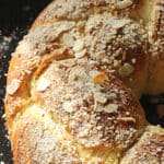 Close up of almond crunch braided bread on black oven sheet; brown and white text overlay