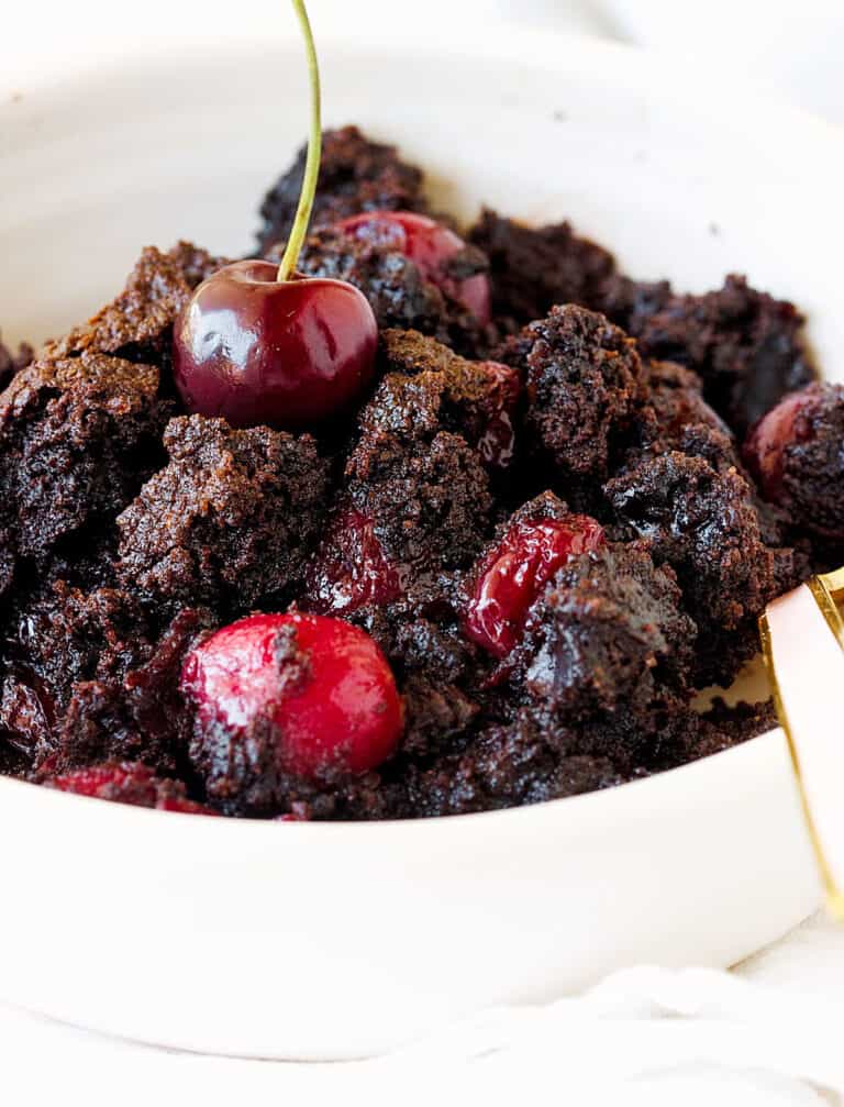 White bowl with chocolate cherry dump cake, a spoon