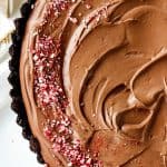 Partial top view of Chocolate mousse pie with crushed candy canes on a white surface.