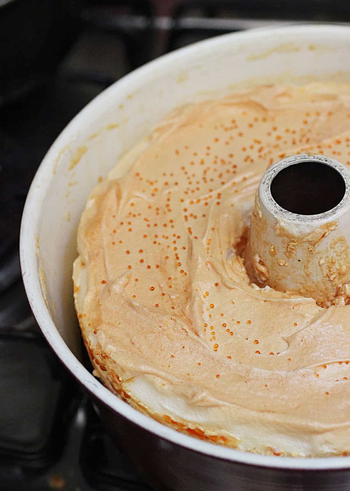 Partial view of tube pan with baked meringue, black surface.