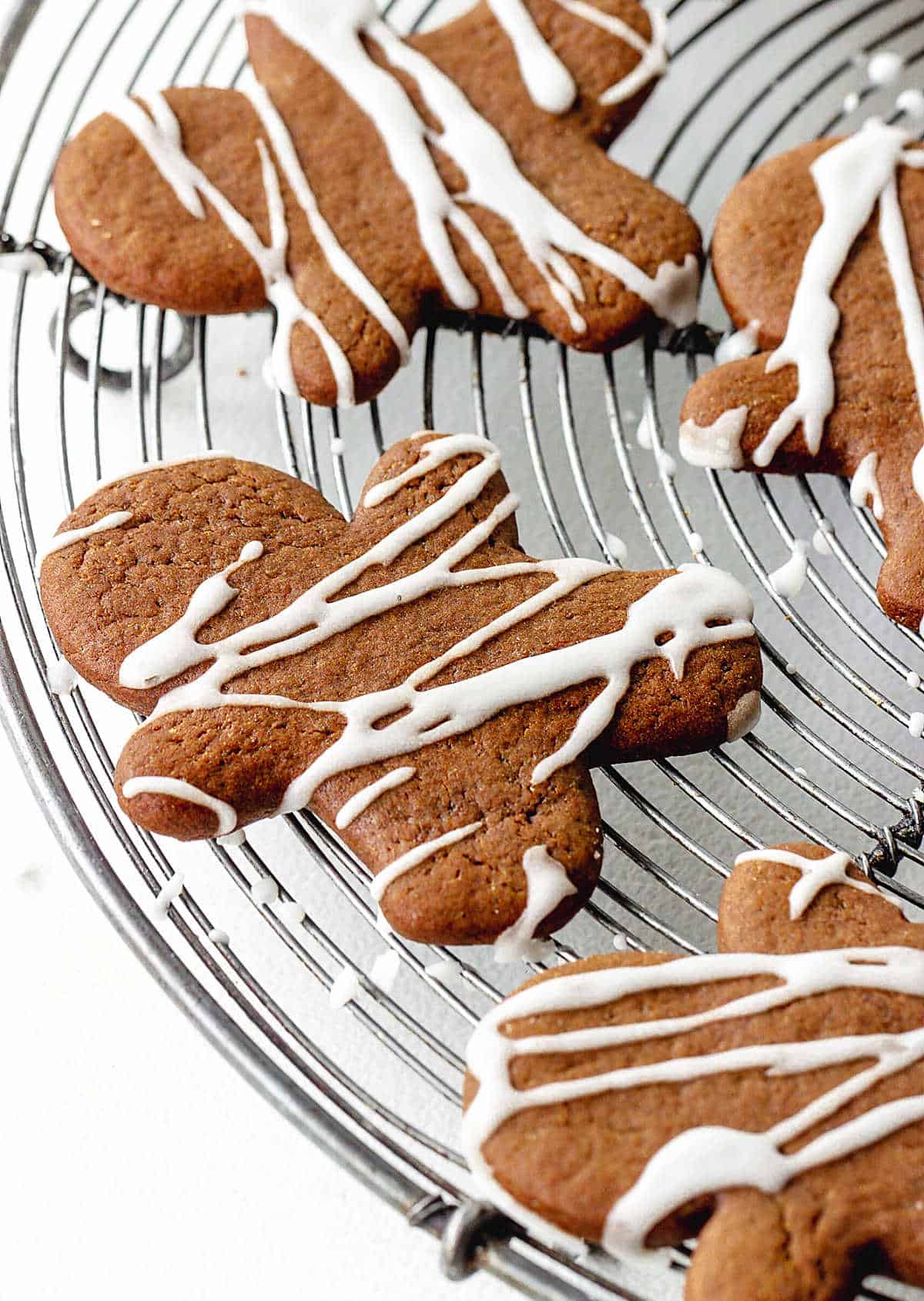 Several gingerbread men cookies with icing on a round wire rack