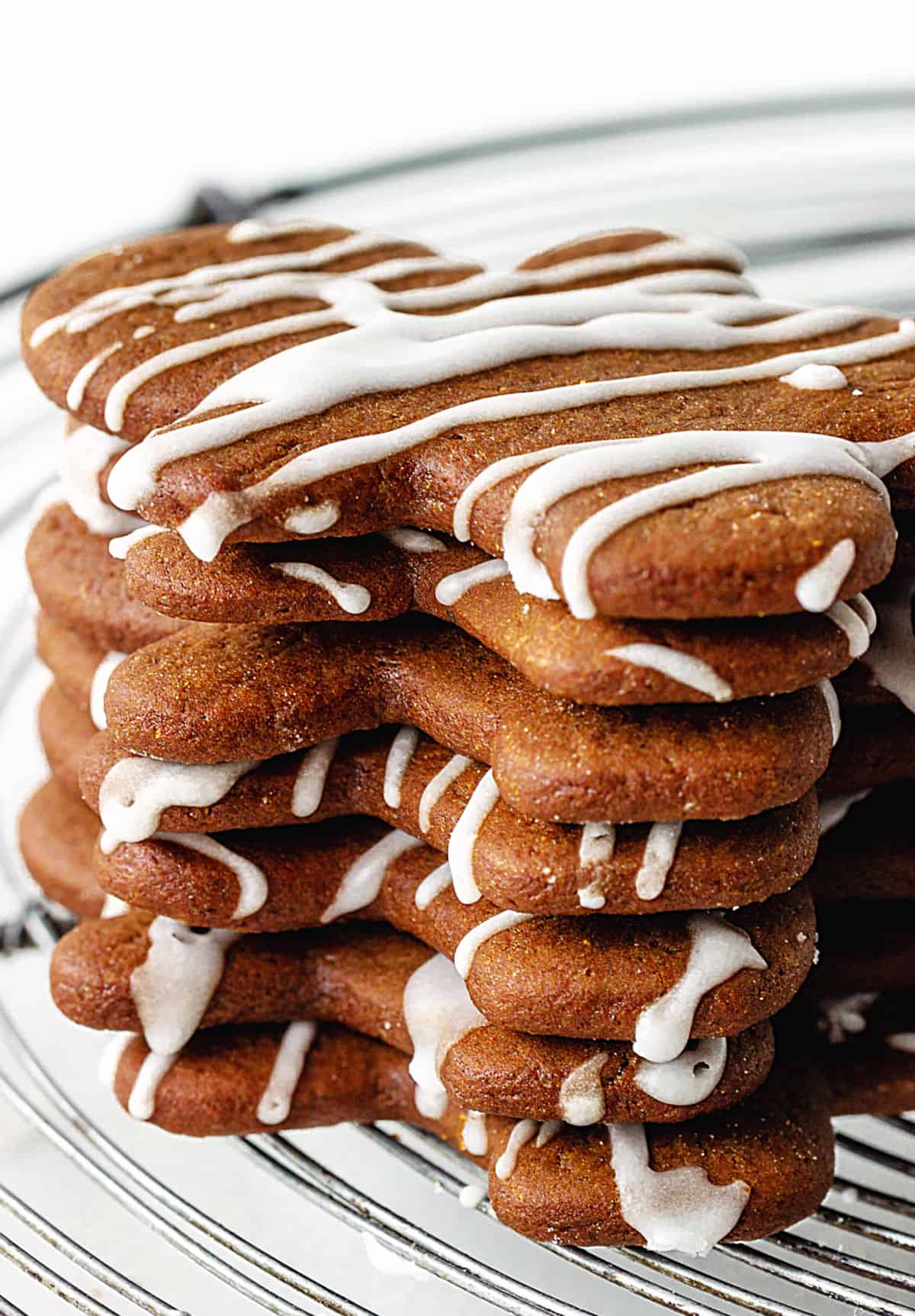 Stack of glazed gingerbread men cookies on a wire rack. 