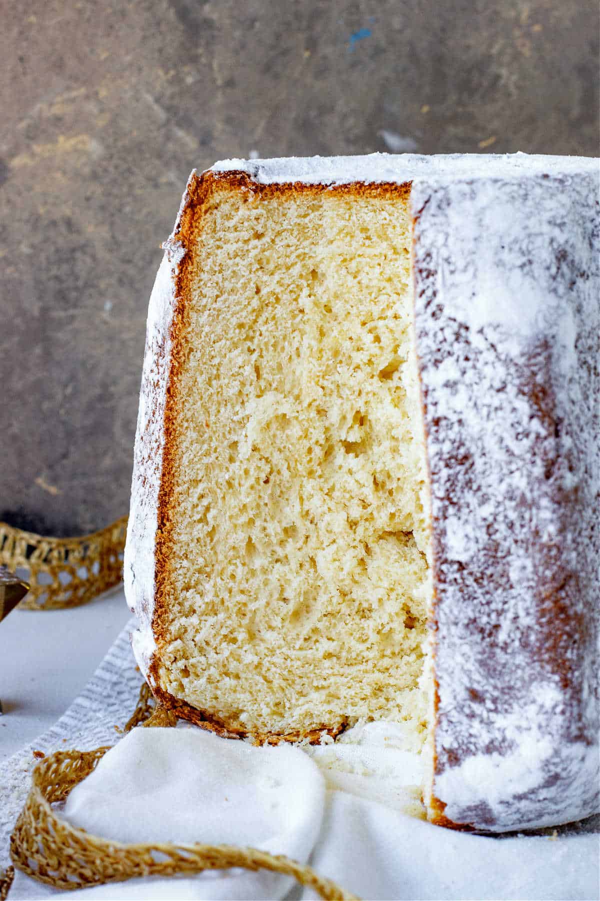 Front view of pandoro bread with missing slice on white, gold and grey surface and background