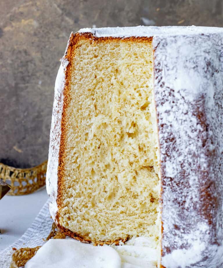 Pandoro bread with exposed crumb on white cloth and golden brown background