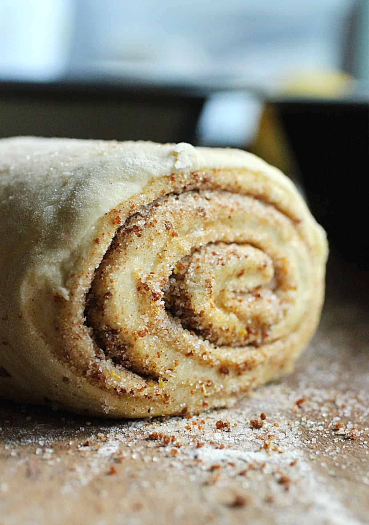 Wooden surface with rolled dough of sweet potato spiced bread.