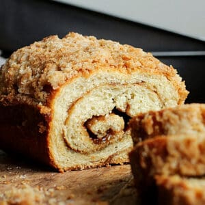 Cut sweet potato cinnamon swirl yeast bread with sugar topping on a wooden table.