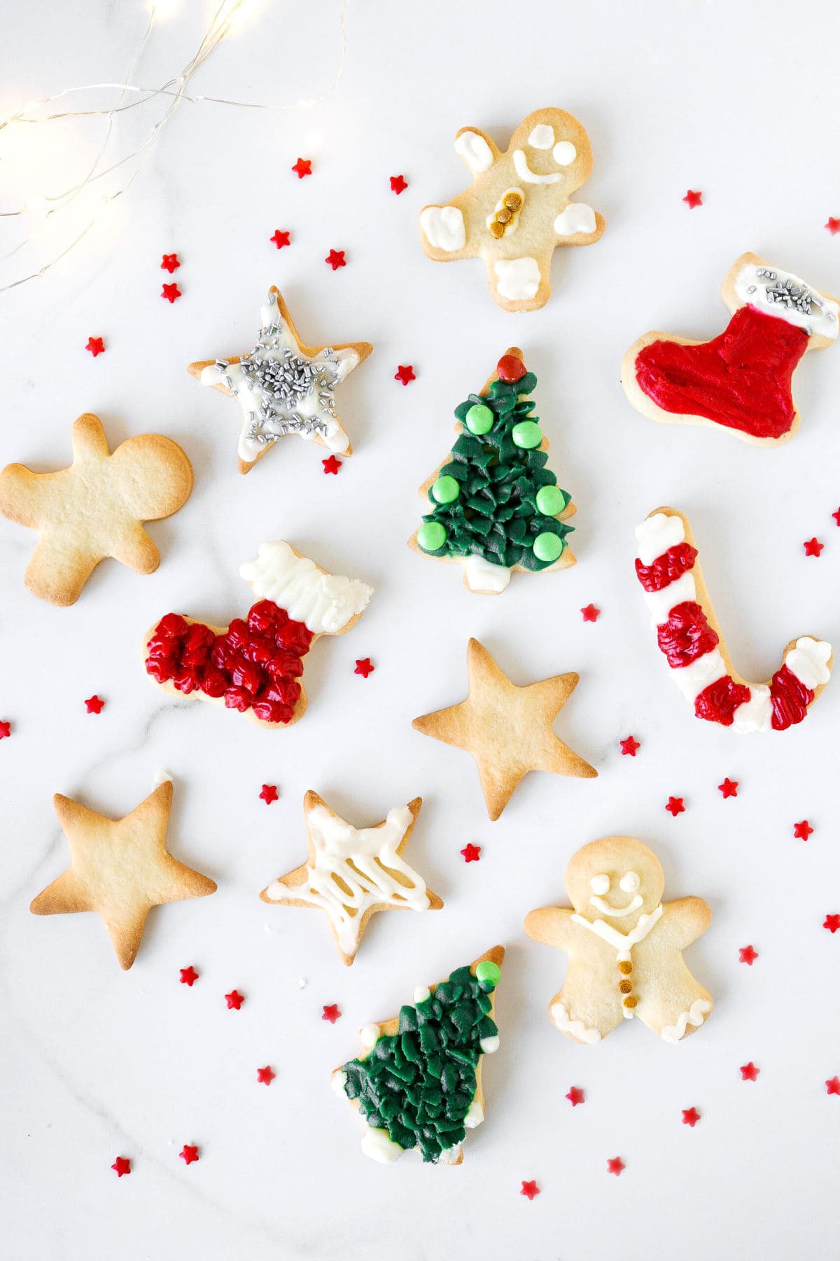 Top view of decorated and plain holiday cut out cookies on a white surface.