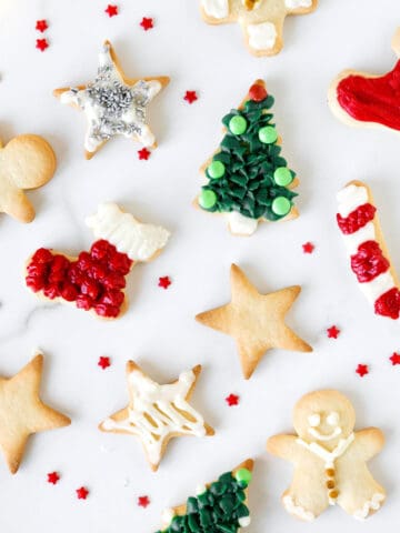 White marbled surface with decorated and plain holiday cut out cookies.