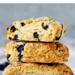 Stack of scones with blueberries on white surface and grey background; purple text on top