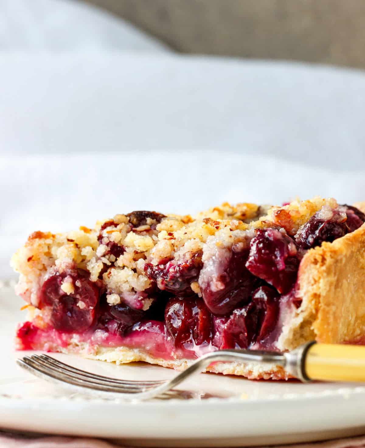 Close up of cherry pie slice on white plate and background